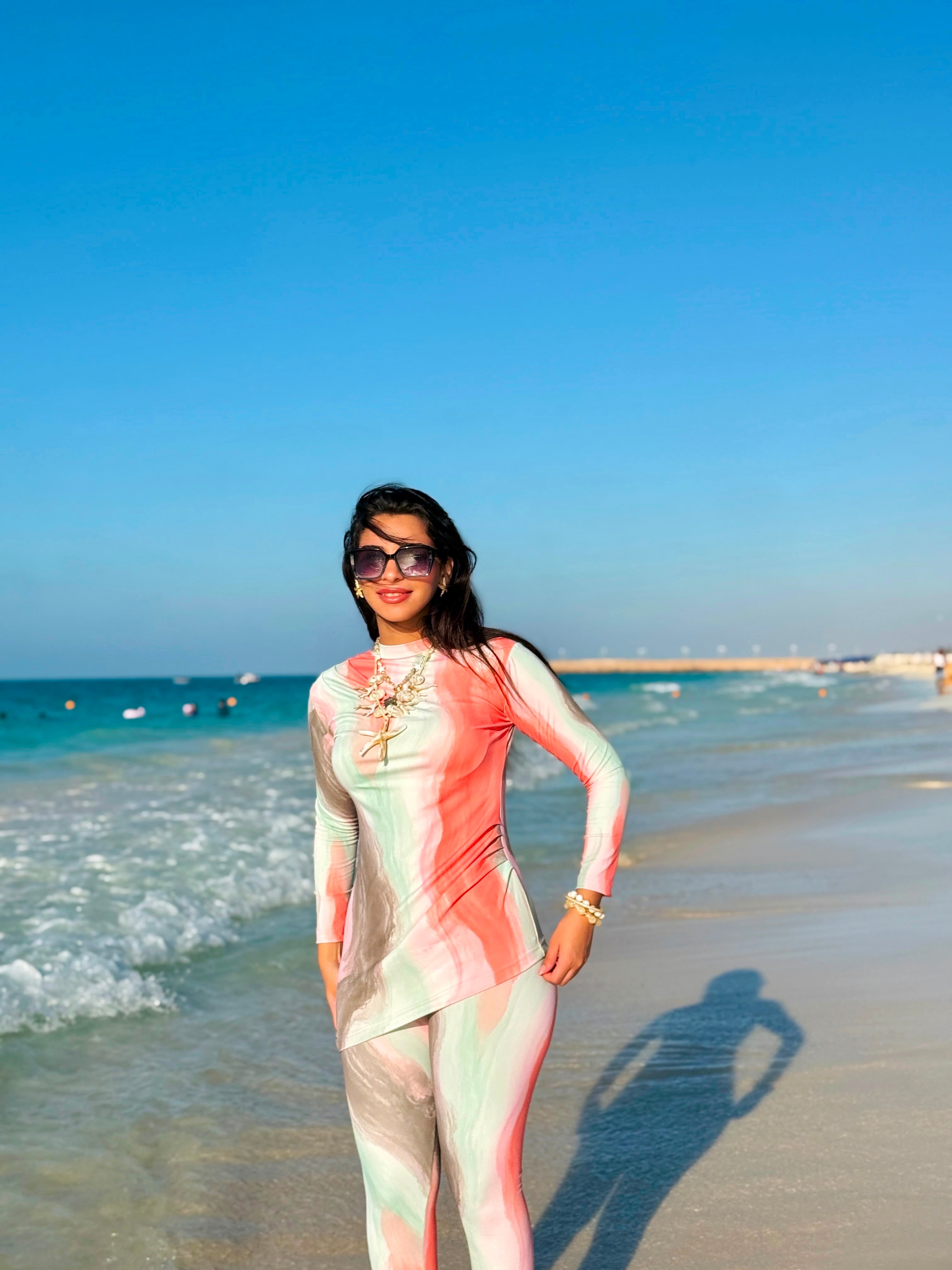 Woman wearing stylish Ta’mayaa swimmers swimwear with long sleeves and colorful gradient design on the beach