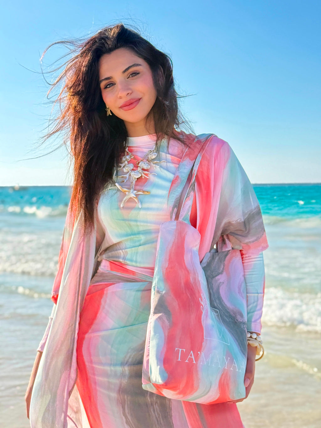 Woman on beach wearing colorful swimmers swimwear with matching cover-up and tote bag by Ta’mayaa