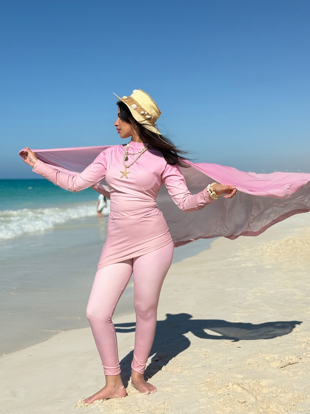 Ta’mayaa modest swimwear in pink covering full body with long sleeves and leggings on beach