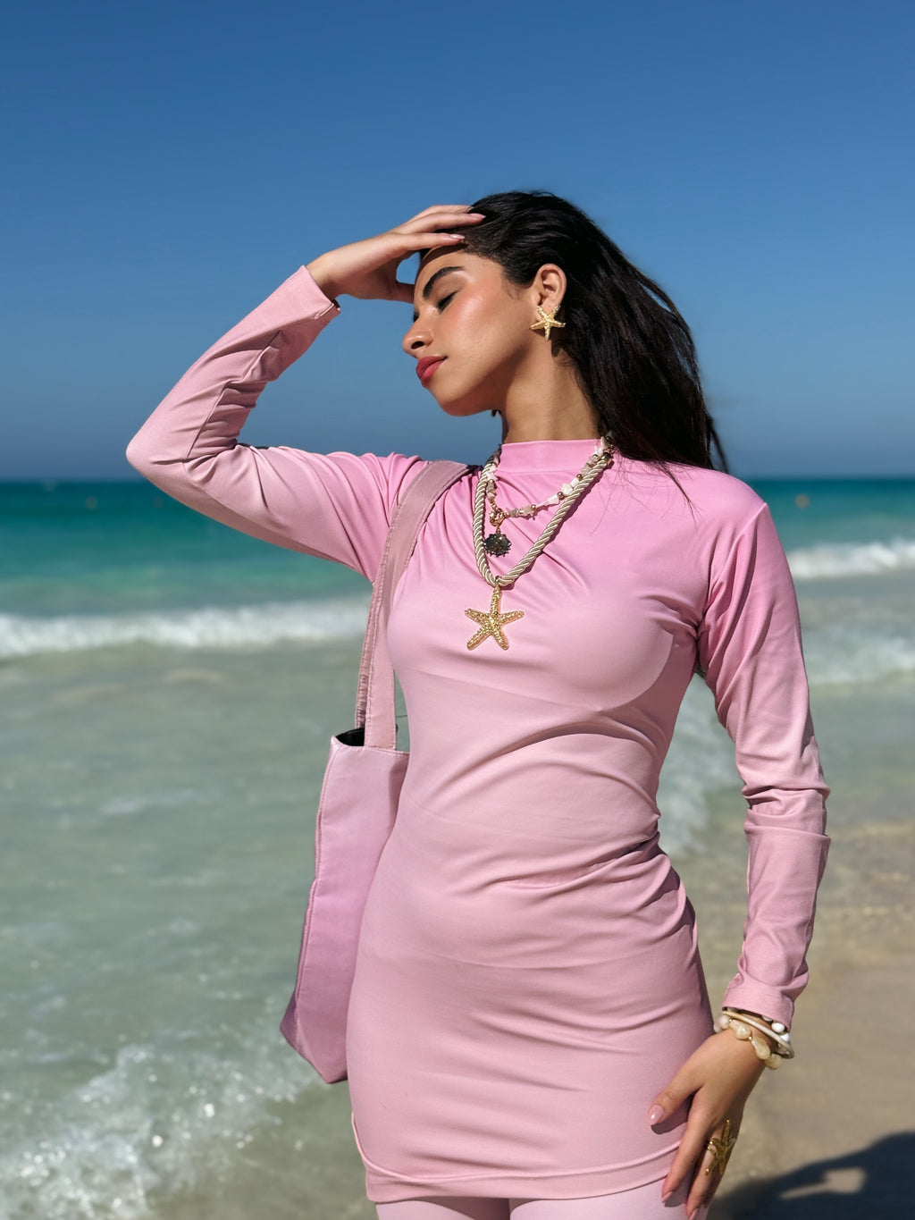 Ta’mayaa pink long sleeve swimwear modest outfit with matching tote bag on woman at beach